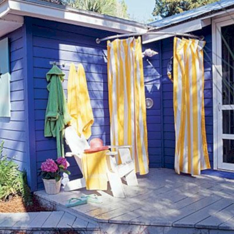 Outdoor shower with yellow and white striped curtain.