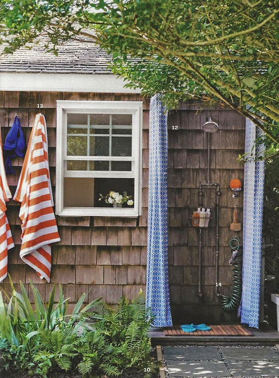 Cottage outdoor shower with blue curtain.