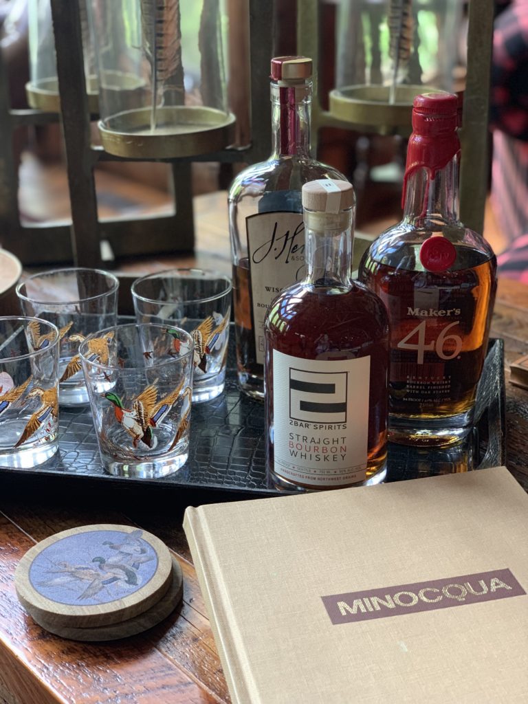 Duck barware glasses sit on a tray next to Bourbon bottles