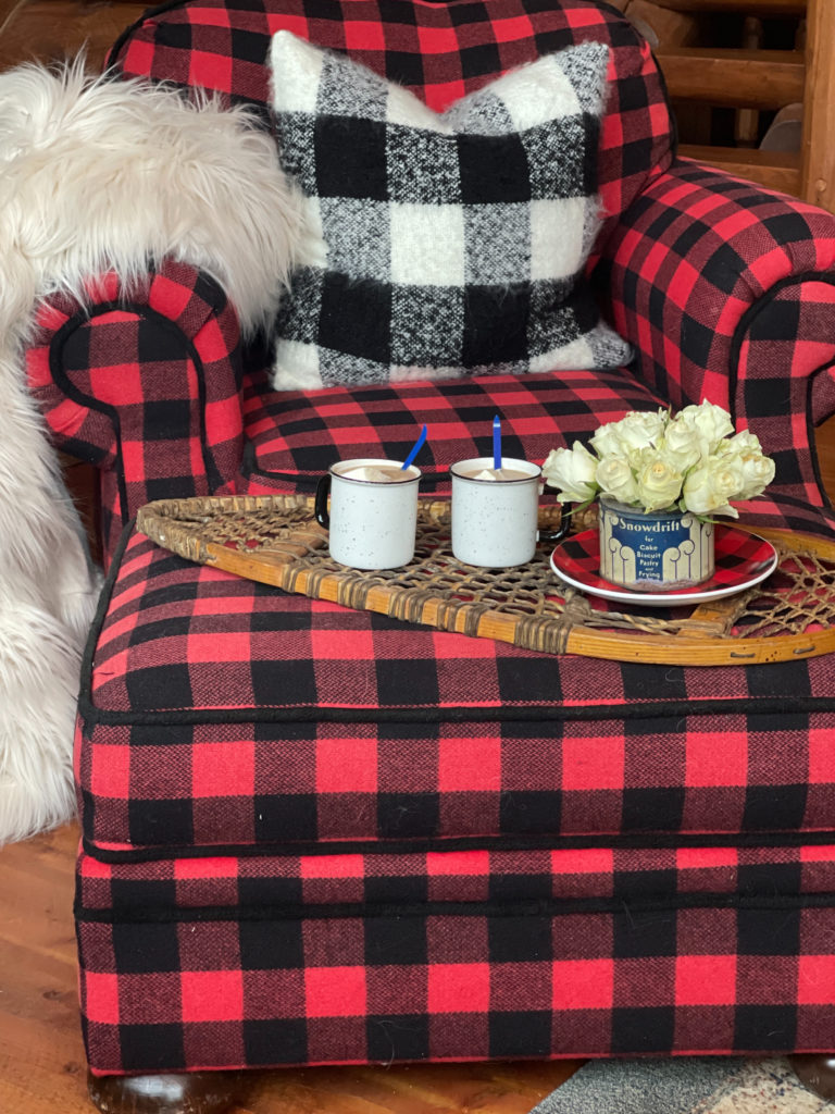 Winter decor of roses in Vintage Snowdrift Tin on buffalo plaid plate on snowshoe tray and hot cocoa