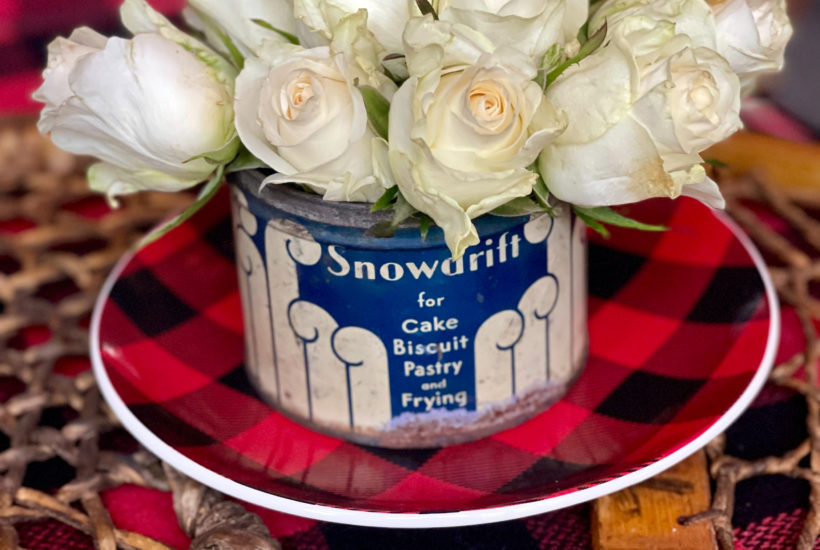 Winter decor of roses in Vintage Snowdrift Tin on buffalo plaid plate on snowshoe tray